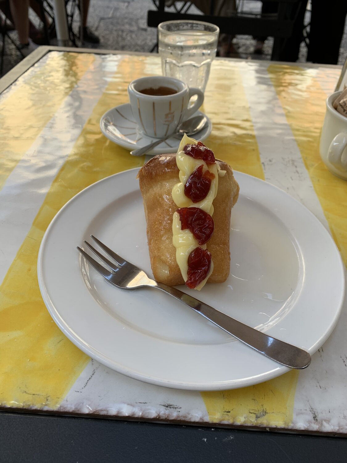 Un maritozzo con la panna, accanto a un caffè, a un tavolino